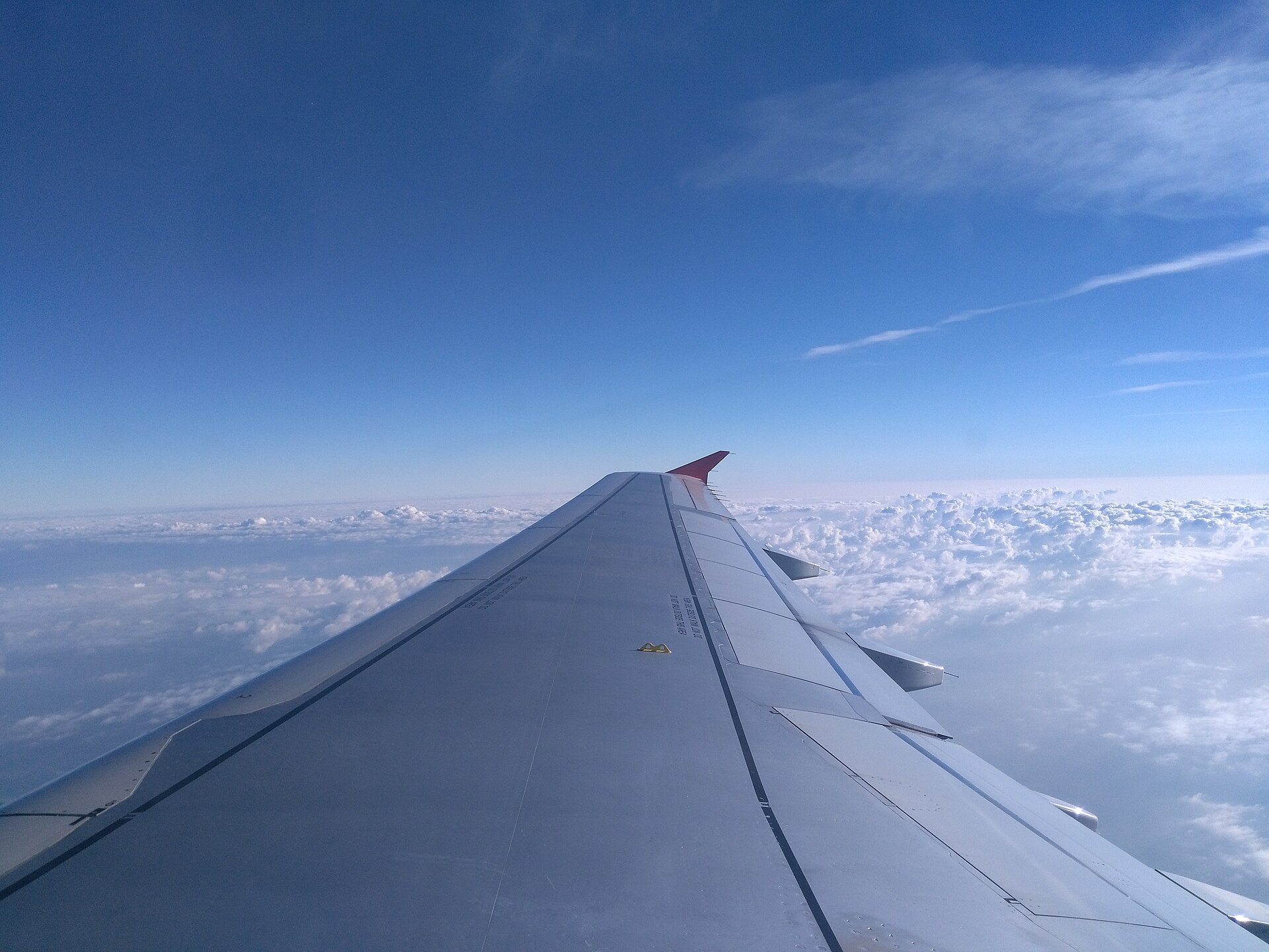 An aircraft wing above a layer of clouds
